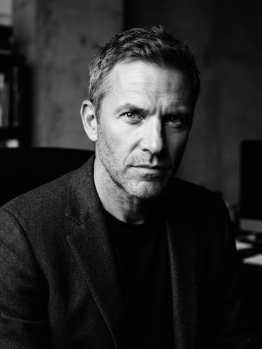 High-contrast black and white editorial portrait of a creative director, sharp focus, dramatic side-lighting, deep shadows, 35mm