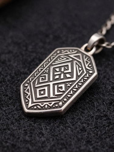Macro shot of traditional Bashkir silver jewelry with detailed geometric engraving, resting on dark felt, dramatic side studio lighting.