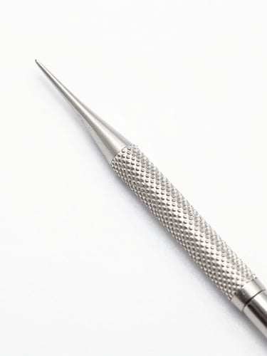 Macro photography of a knurled dental scaler grip on a seamless clinical white backdrop, bright high-key lighting, crisp studio light, sharp focus on steel texture.