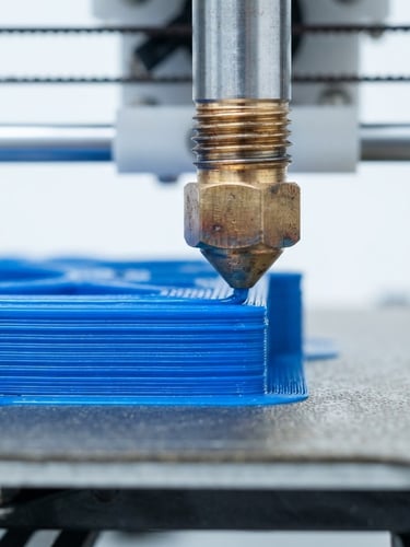 Macro close-up of a high-precision 3D printer nozzle extruding a blue technical polymer layer by layer, sharp focus on the crisp layer lines, cool studio lighting, clean white workshop background