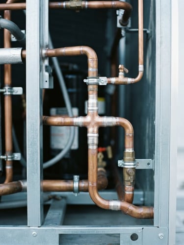 Close-up of clean copper piping welds on a pristine commercial condenser unit, bright crisp utility lighting, cool metallic tones, high-contrast 35mm