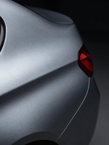 Extreme close-up 2–3 cm macro of a matte-to-metallic vinyl wrap edge transition on a BMW door panel, cool studio side lighting revealing surface texture depth and a perfectly flush seam, dark background, no glare
