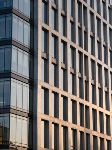 Elegant modern corporate building facade made of glass and steel, soft natural daylight of late afternoon, warm champagne tones, architectural composition, 35mm lens