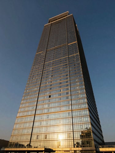 Wide-angle architectural shot of Marina Bay Towers in Mumbai, warm golden-hour sunlight reflecting off modern glass facade, deep navy sky, crisp 35mm lens.