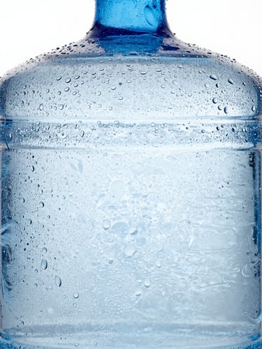 Crisp studio product photography of a premium 20L water can with condensation droplets, clean glass textures, cool high-key lighting with deep blue tones