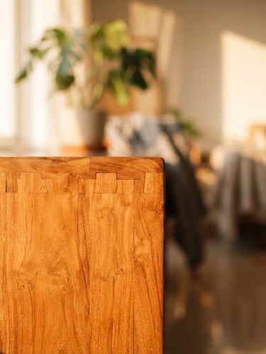 Close-up of hand-finished teak wood joinery in a bright Bangalore apartment, warm afternoon sunlight casting soft shadows, rich orange tones, shallow depth of field