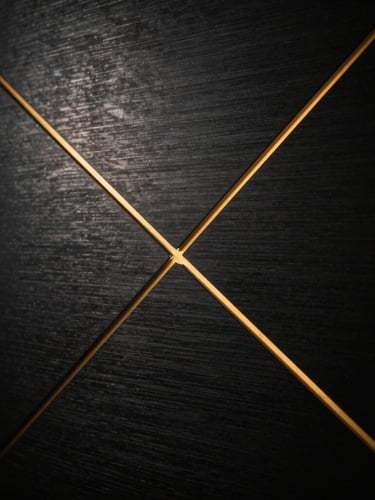 Cinematic dark photography, macro shot of a dark brushed titanium panel with razor-thin gold geometric lines, dramatic single-source side lighting, 35mm