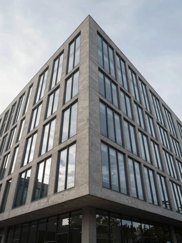 Wide architectural exterior shot of a modernist building façade, raw concrete and glass panels meeting at a precise right-angle junction, soft overcast north-facing daylight, unoccupied, framed from low angle to emphasize vertical geometry and material weight, generous sky above