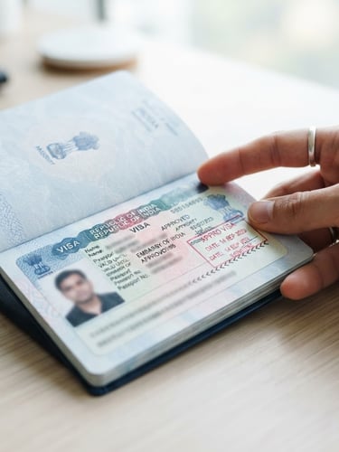 Close-up of a hand carefully reviewing an approved visa stamp inside an Indian passport, clean editorial photography, bright natural daylight, crisp blue and white tones, shallow depth of field