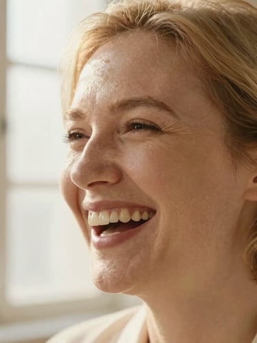 A close-up portrait of a professional laughing naturally, warm editorial photography, soft golden light, shallow depth of field
