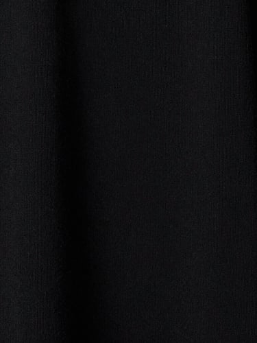 Extreme close-up on the heavy, custom-milled loopback cotton texture of a black garment, high-contrast studio lighting, showing the raw weave detail.