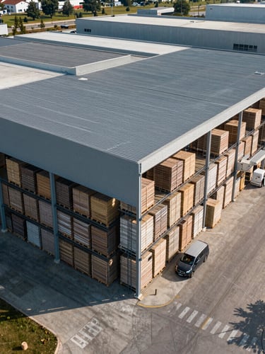 Vista aérea de un almacén industrial organizado con palés listos para distribución, iluminación clara y estructura metálica simétrica.