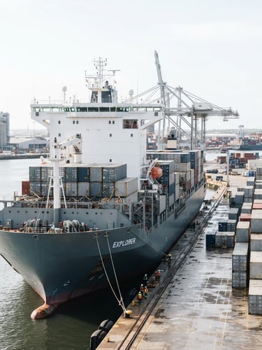 Bright, high-key daylight shot of a modern deep-water container ship at port, sharp focus, clean corporate photography, slate and white tones, 35mm.