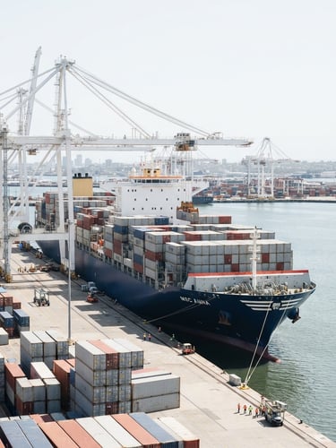Wide-angle corporate photography of a modern deep-water container ship at port under bright high-key daylight, clean slate and white tones, sharp focus, 35mm