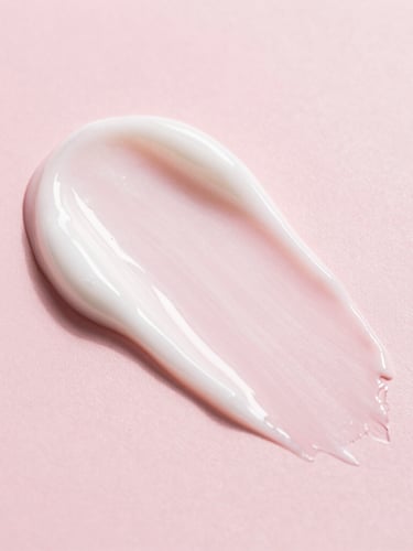 Macro texture close-up of a rich, hydrating cream being gently spread on diverse skin, showing soft light reflection, pastel pink background, clean beauty product photography, soft diffused daylight, minimalist composition, 50mm lens.