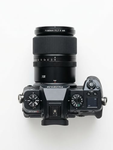Bright high-key studio product photography of a premium mirrorless camera and lens on a clean white background, sharp focus, overhead layout