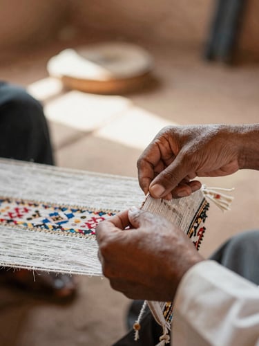 A warm close-up of hands weaving a traditional textile in a cooperative workshop in Morocco, soft natural side lighting, authentic regional setting, 35mm lens