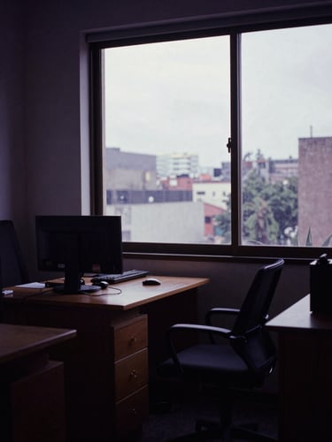 Moody film photography of a CDMX production office interior, soft overcast daylight through a high window, deep shadows, cinematic 35mm