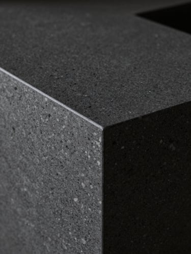 Extreme close-up of a flawless 45-degree miter joint in a dark charcoal quartz sinter countertop, dramatic side-lighting, sharp focus on texture, architectural interior photography.