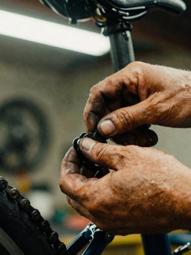 Close-up of grease-stained hands adjusting a bicycle chain inside a raw workshop, warm lighting, high contrast, 35mm film grain.