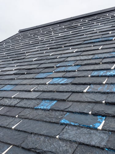 Close-up of perfectly aligned dark slate tiles and hand-soldered zinc joints on a steep roof, overcast daylight, architectural photography, sharp focus, 35mm lens