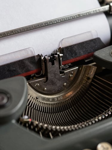 Extreme close-up of a vintage typewriter key striking a crisp white page, ink ribbon texture visible, high-contrast shadows.