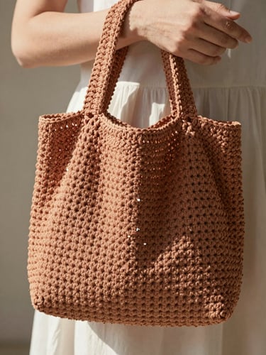 Close-up of elegant hands holding a neutral terracotta crochet bag, soft natural daylight filtering from the side, highlighting the intricate stitch texture, shallow depth of field, 35mm