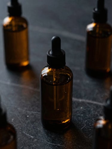 Close-up of premium amber glass skincare bottles on a dark textured marble surface, warm amber light glinting off the glass, dramatic low-key lighting