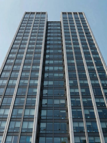 Symmetrical architectural shot of a modern glass and steel skyscraper facade rising into a clear sky, sharp high-contrast daylight, clean geometric lines, minimalist composition.