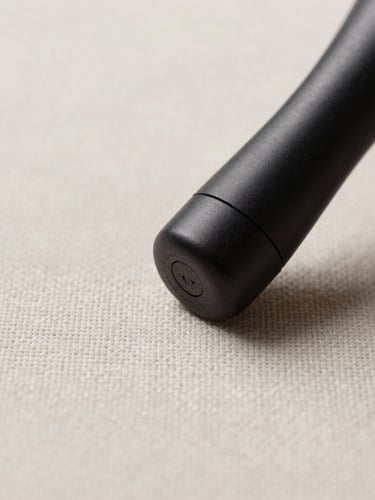 Macro close-up of a textured luxury linen fabric being treated with a sleek matte-black extraction tool, crisp gallery lighting, desaturated tones