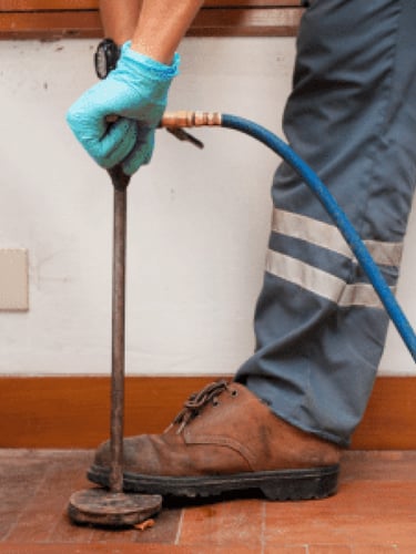 Professional pest control technician using a soil injector for termite treatment in a home.