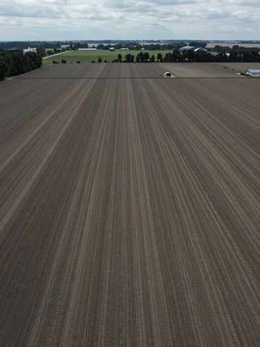 High-altitude aerial drone photograph of a working farm with clear boundary lines, natural overcast daylight, realistic desaturated tones, high detail.