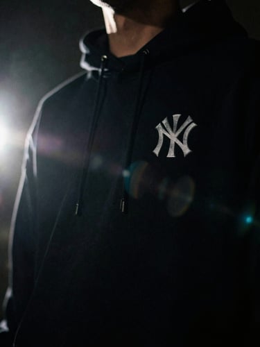 Low-key dramatic close-up of premium streetwear, anamorphic lens flare, high contrast dark tones, vertical 9:16 framing