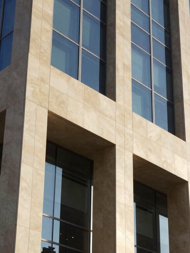 A close-up architectural shot of modern glass and steel facade of a banking headquarters in Doha, bright daylight, sharp focus on premium materials.