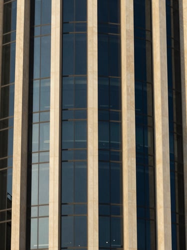 Close-up of modern architectural steel and reflective glass facade in Doha, captured in crisp morning light with deep navy shadows