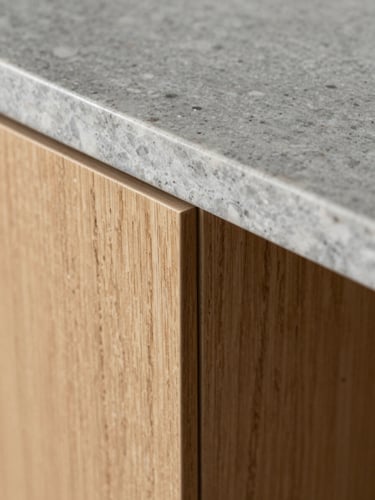 Macro close-up of a perfect material transition, light oak wood panel meeting a brushed grey quartzite countertop, razor-thin shadow gap, soft side lighting