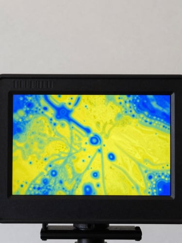A high-contrast close-up of a thermal imaging camera screen displaying bright yellow and blue moisture maps behind a drywall, sharp documentary photography