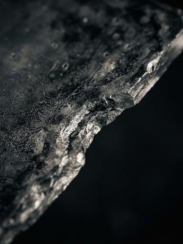 Extreme macro shot of a wet-plate glass edge, rich silver tones, dramatic low-key side lighting, deep charcoal background.
