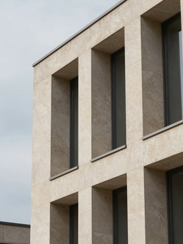 Close-up architectural detail of a modern limestone building facade, sharp geometric shadows, overcast daylight, minimalist aesthetic.