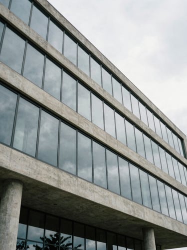 Wide angle architectural crop of modern concrete and glass structure facade under overcast Lowcountry sky, highlighting clean geometric lines.