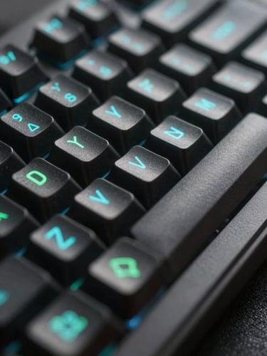 Extreme macro shot of a dark mechanical keyboard with glowing cyan and green keycap legends, shallow depth of field, screen reflection.