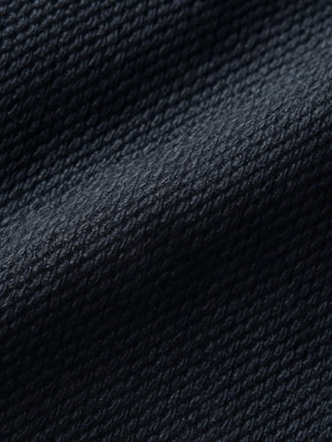 Macro close-up of deep navy heavy-weight cotton fabric, emphasizing the tight weave and texture, soft studio side-lighting, rich cream and deep navy tones.