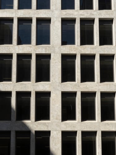 Architectural detail of a modern concrete office facade in Los Angeles, hard directional daylight, deep slate shadows, minimalist structural lines, 35mm lens