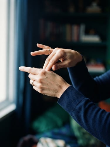 Close-up of hands performing a complex sign in Libras, soft natural window light, deep navy and emerald tones, shallow depth of field, 35mm, focus on the intricate hand movement, a subtle cool overlay.