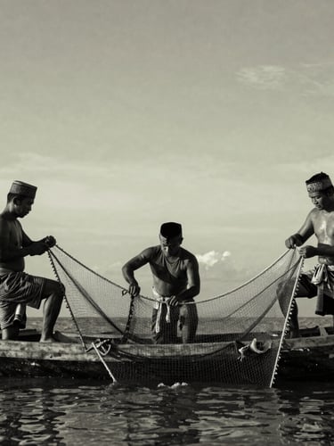 Historical archival style black and white photograph of traditional Acehnese sailors and fishermen working with nets on a wooden vessel, dramatic natural light, rich textures, respectful framing.