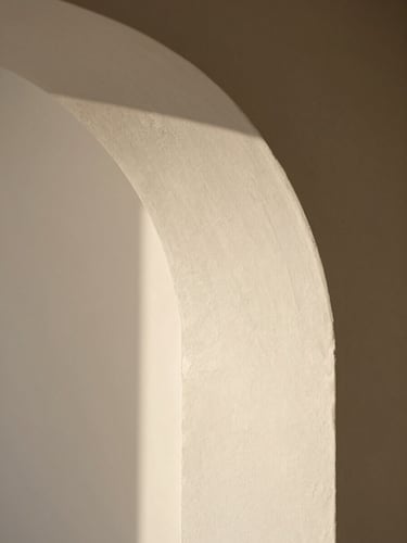 Close-up of soft morning light casting a curved shadow on a textured plaster wall, minimalist architectural detail, warm neutral tones, shallow depth of field