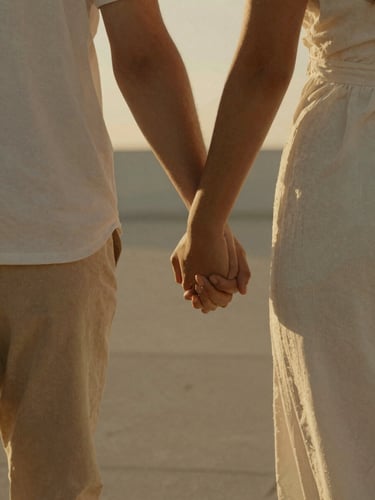 A candid close-up of a couple holding hands while walking through a sun-drenched minimalist venue, warm golden hour light, cinematic 35mm film grain.