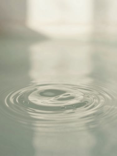 Macro shot of gentle ripples in clean water, soft natural daylight, calming sage and off-white tones, shallow depth of field, 35mm