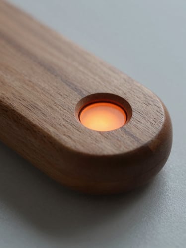 Tactile close-up of a wooden hand-held navigation device with smooth rounded edges, warm studio lighting, soft shadows, focusing on a subtle orange light indicator.