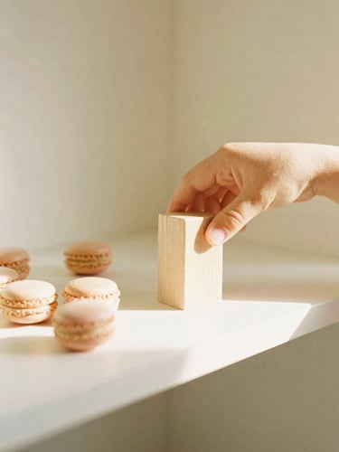 Hands of a child sorting smooth wooden blocks on a low cream-colored shelf, soft morning sunlight, warm editorial style